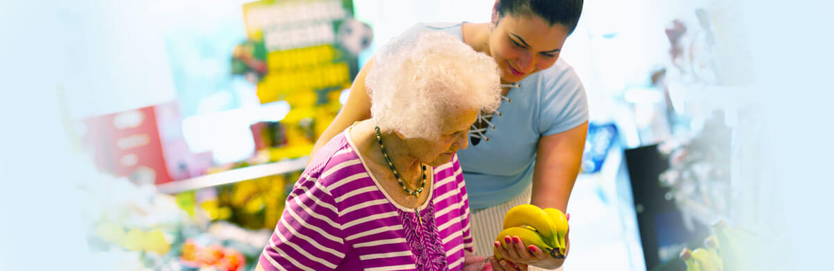 Caregiver helping elderly client shop for produce